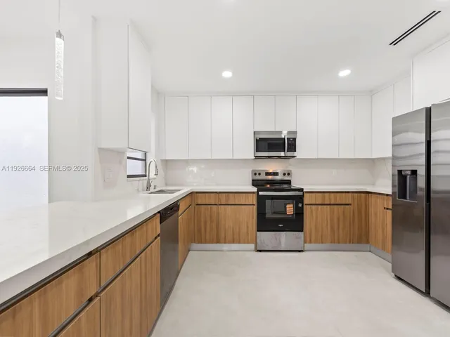 a kitchen with granite countertop a refrigerator and a stove top oven