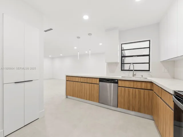 a view of a kitchen with a sink and dishwasher a refrigerator with white cabinets