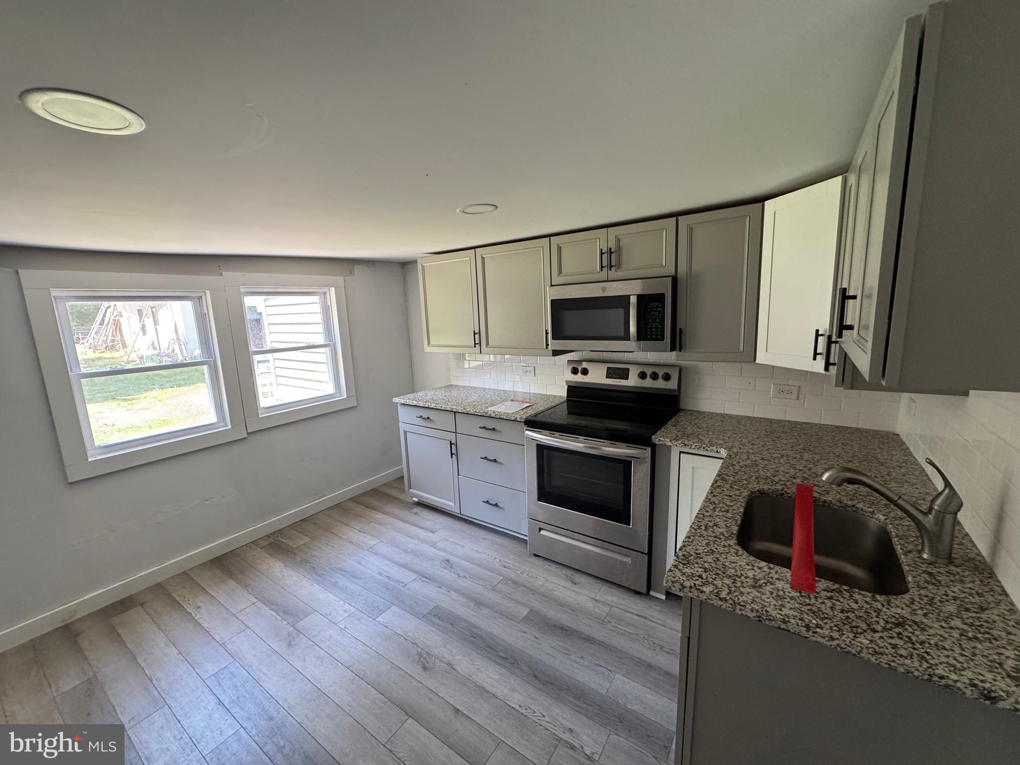 395 Tansboro Road Berlin, NJ 08009 - Photo 13 of 47 a kitchen with granite countertop a stove a sink and a microwave