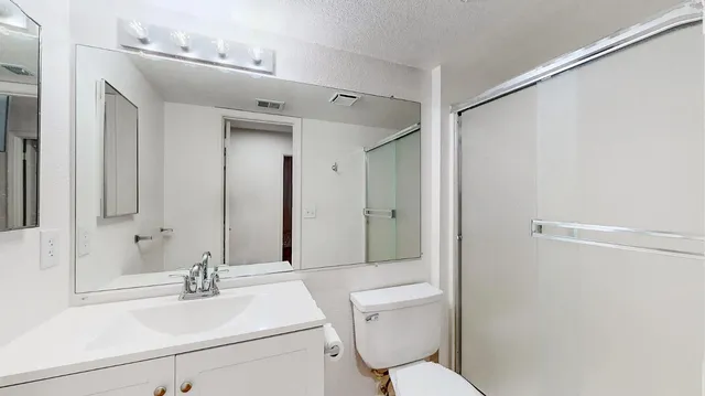 an empty room with wooden floor chandelier fan and windows