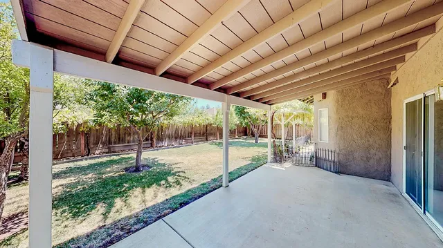 a backyard of a house with table and chairs and a large tree