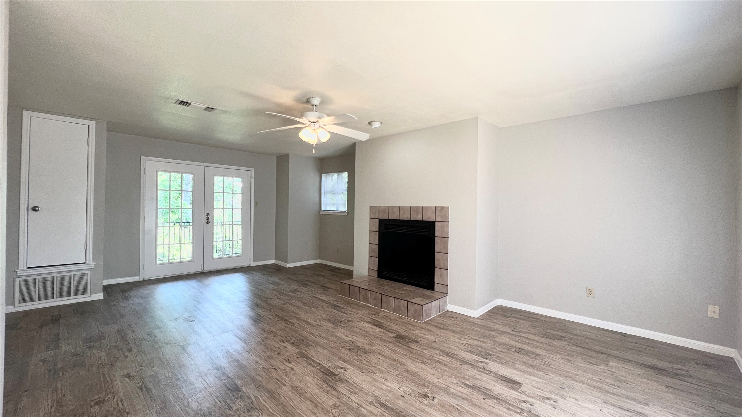 9201 Simmons Road, Unit 117 Austin, TX 78759 - Photo 3 of 20 French doors open to an inviting living area with rich wood flooring and a cozy corner fireplace.