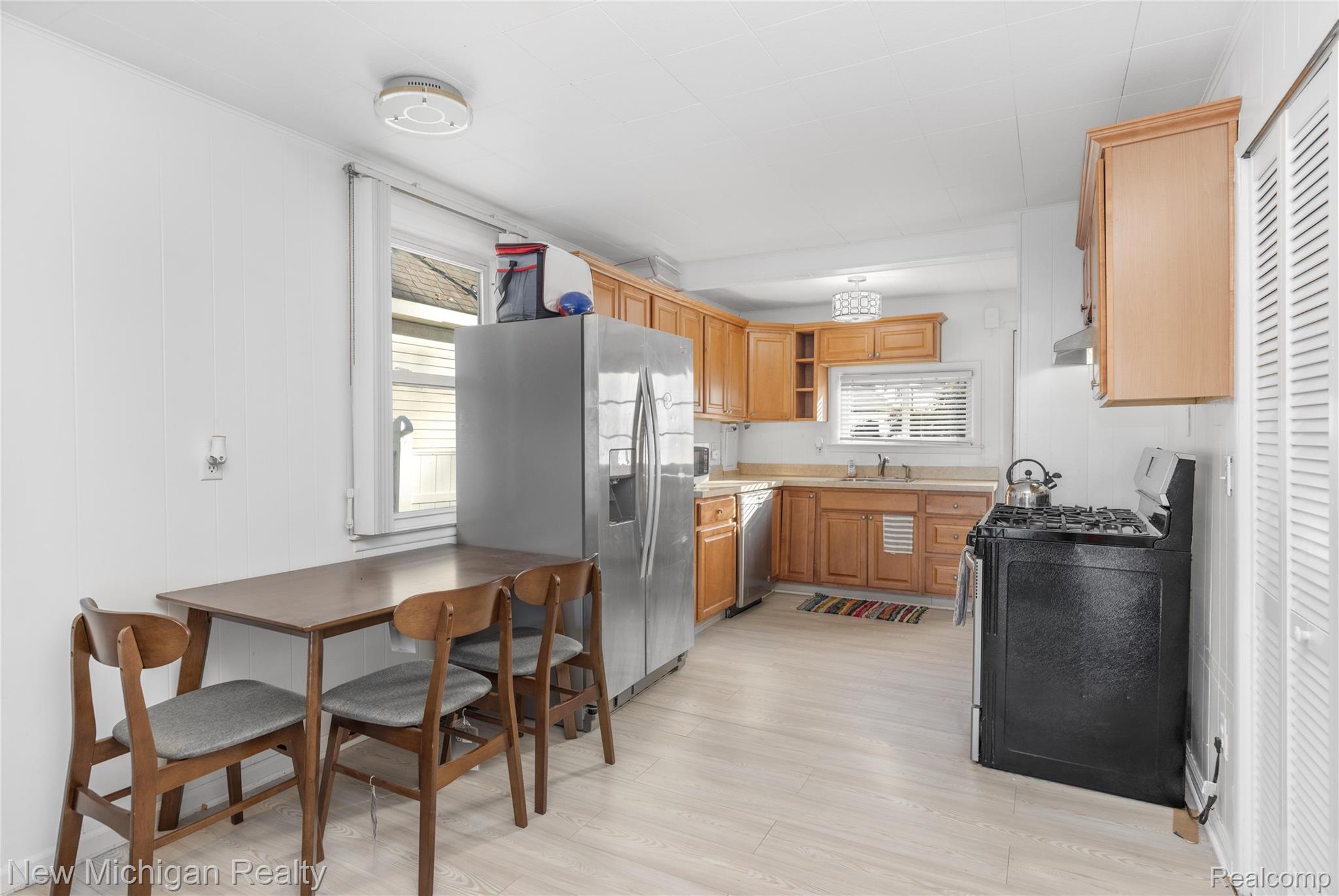 8665 Cooley Lake Road Commerce Township, MI 48382 - Photo 21 of 52 Kitchen featuring stainless steel appliances, light countertops, plenty of natural light, light wood-style flooring, and wood walls