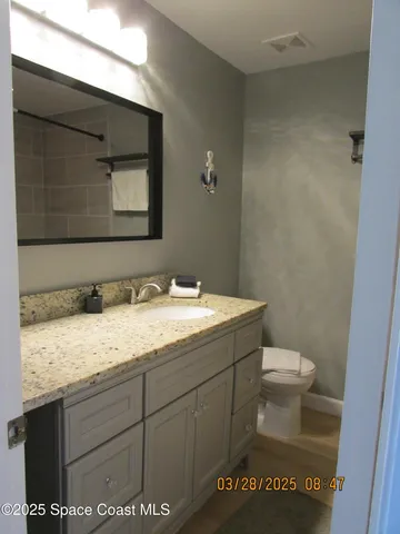 a bathroom with a granite countertop sink a toilet and a mirror