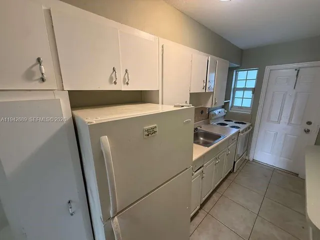 a kitchen with sink a refrigerator and cabinets