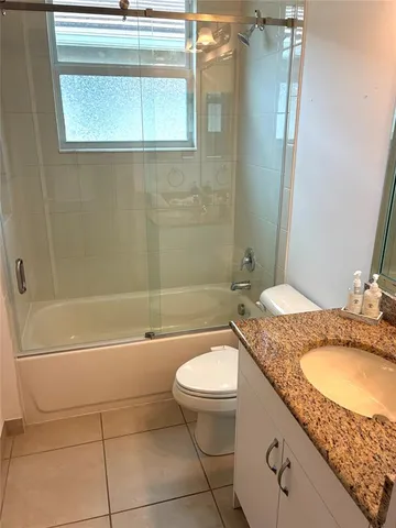 a bathroom with a granite countertop sink toilet mirror and bathtub
