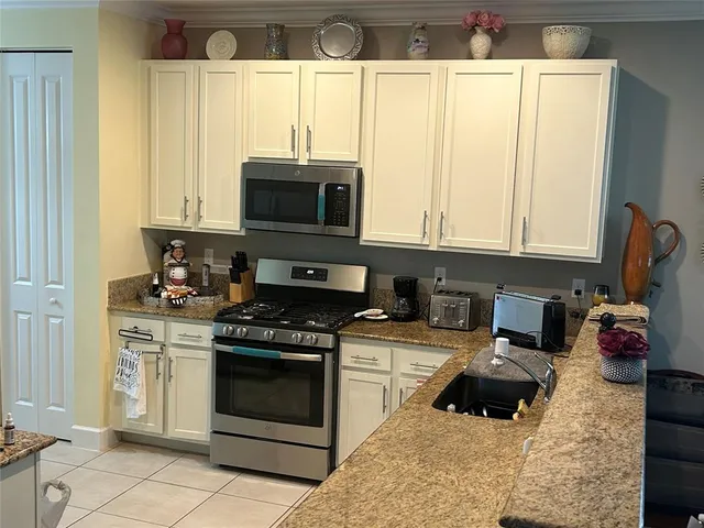 a kitchen with granite countertop a stove a sink and a microwave
