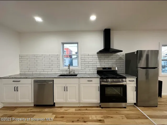 a kitchen with stainless steel appliances granite countertop a stove a sink and a refrigerator