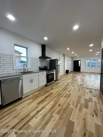 a large kitchen with stainless steel appliances granite countertop a sink and cabinets