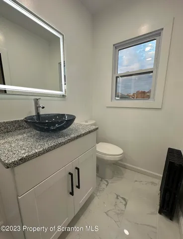 a bathroom with a granite countertop sink a toilet and a mirror