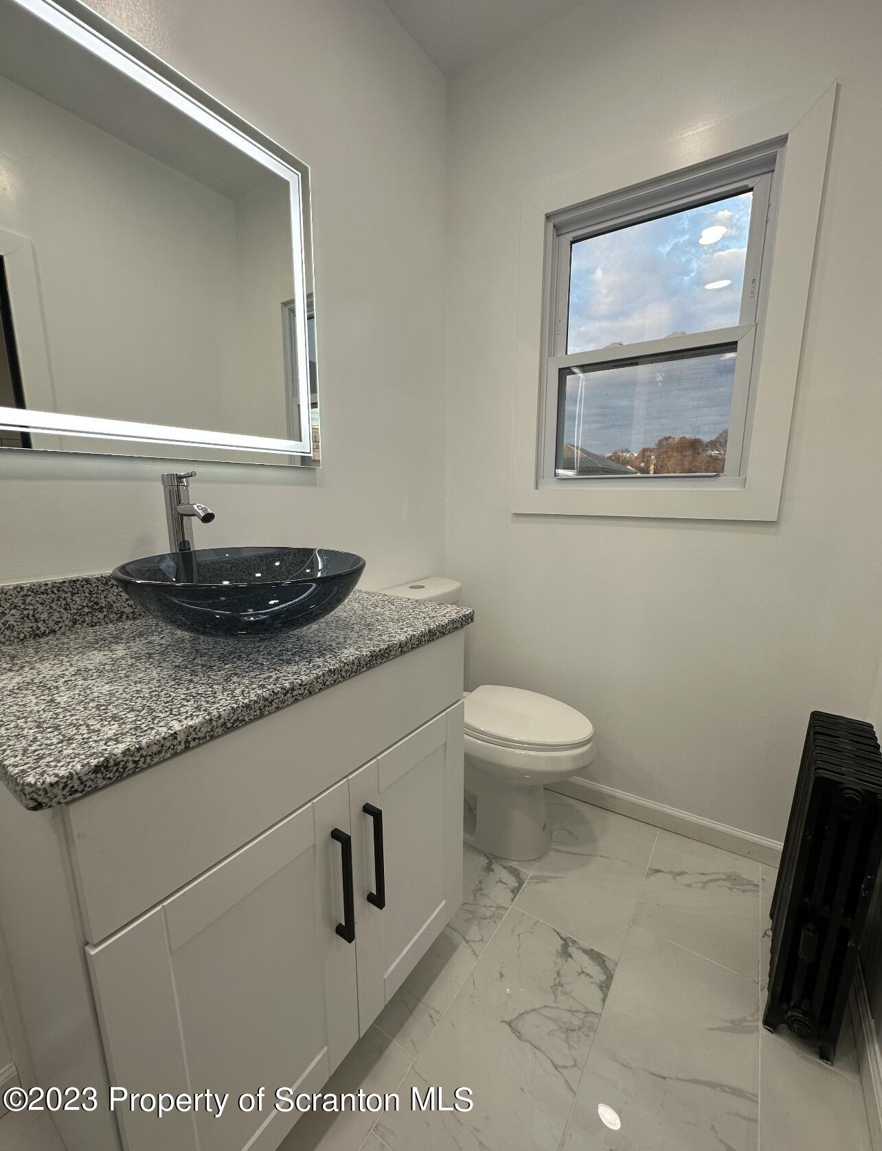 301 Oak Street Old Forge, PA 18518 - Photo 10 of 19 a bathroom with a granite countertop sink a toilet and a mirror