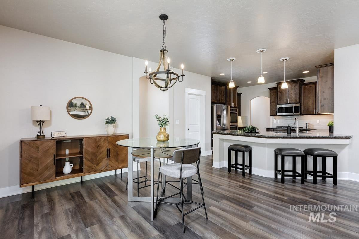 3902 North Rotaldo Avenue Meridian, ID 83646 - Photo 11 of 34 Dining space with arched walkways, a chandelier, dark wood-type flooring, and recessed lighting