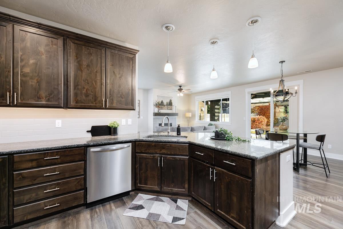 3902 North Rotaldo Avenue Meridian, ID 83646 - Photo 14 of 34 Kitchen featuring dark brown cabinets, dark stone counters, hanging light fixtures, and dishwasher