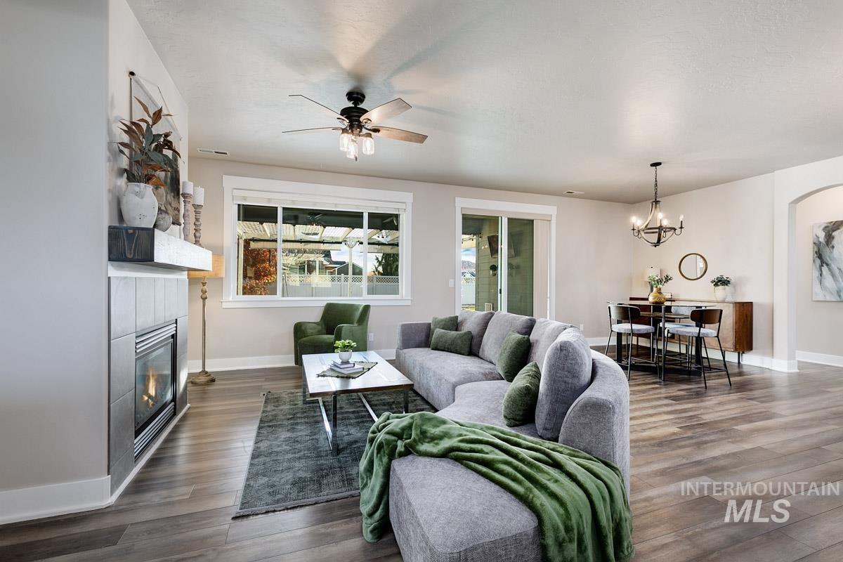 3902 North Rotaldo Avenue Meridian, ID 83646 - Photo 7 of 34 Living room featuring dark wood-style flooring, a ceiling fan, a chandelier, and a fireplace