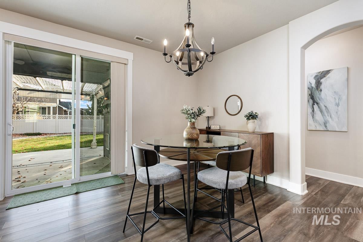 3902 North Rotaldo Avenue Meridian, ID 83646 - Photo 10 of 34 Dining space featuring arched walkways, dark wood-style flooring, and a chandelier