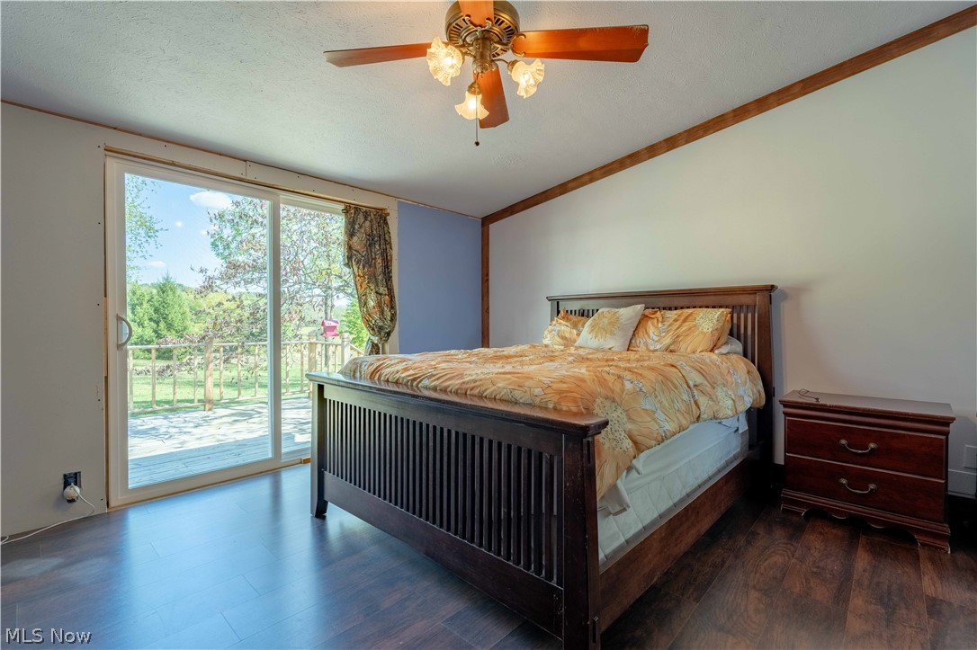 5267 Apollo Road Northeast Salineville, OH 43945 - Photo 14 of 33 Bedroom featuring access to outside, vaulted ceiling, dark wood finished floors, a ceiling fan, and a textured ceiling