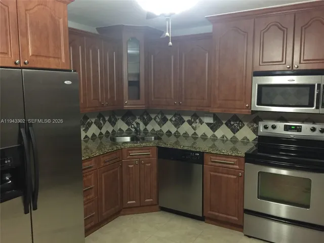 a kitchen with granite countertop a stove top oven microwave and cabinets