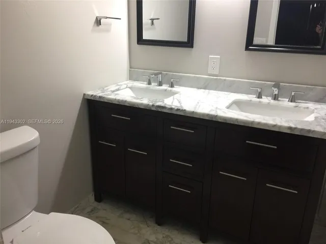 a bathroom with a granite countertop sink toilet and mirror