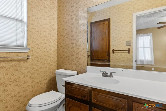 a bathroom with a granite countertop sink toilet a mirror and a window