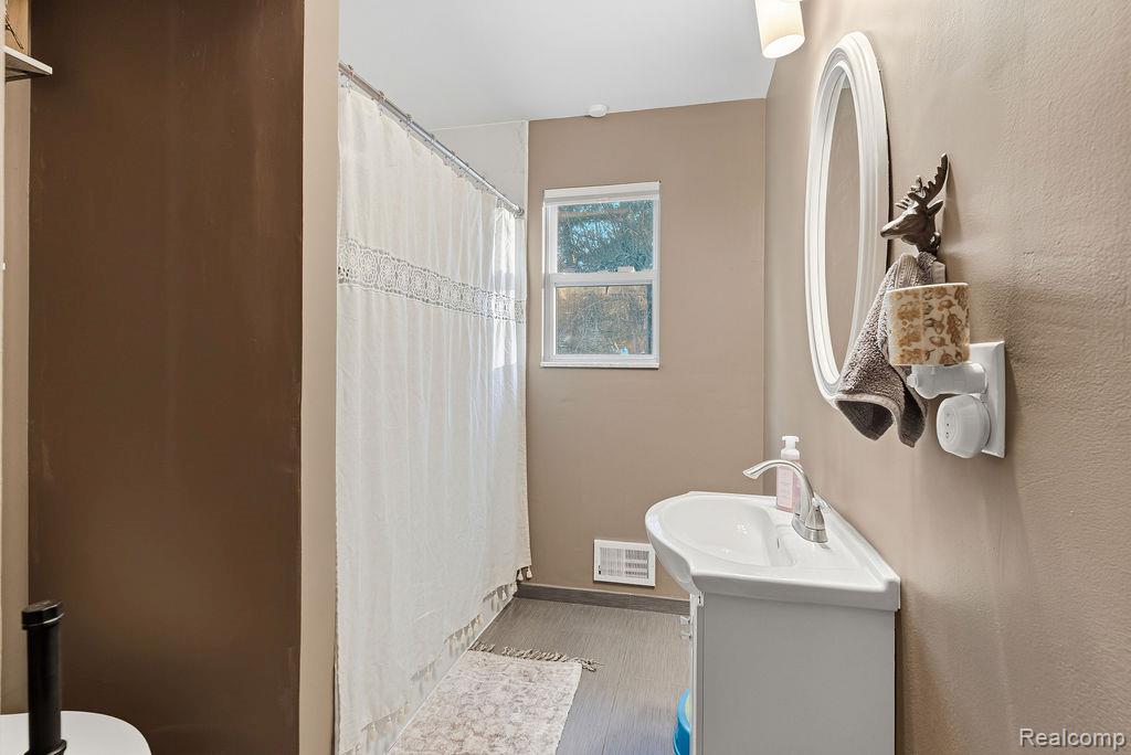 5216 South State Road Goodrich, MI 48438 - Photo 19 of 52 Bathroom with curtained shower, vanity, and wood finished floors