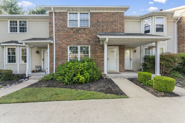 a view of a brick house with plants and large tree