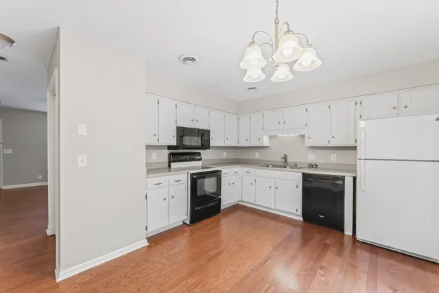 a kitchen with white cabinets stainless steel appliances and wooden floor