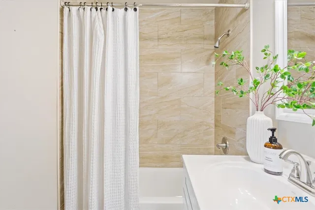 a bathroom with a sink a bathtub and potted plant