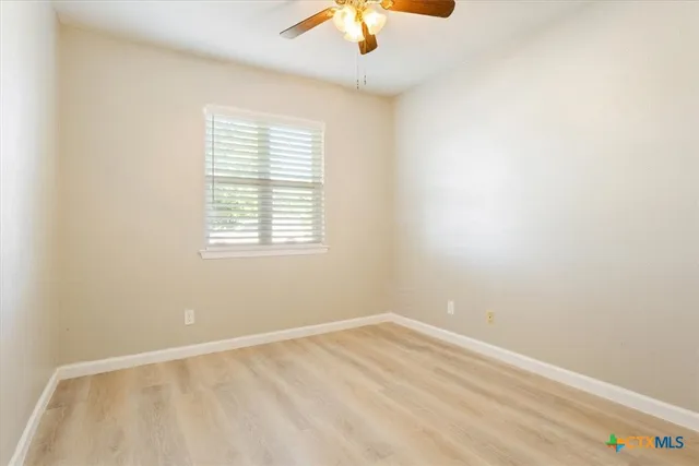 an empty room with a window and a fan