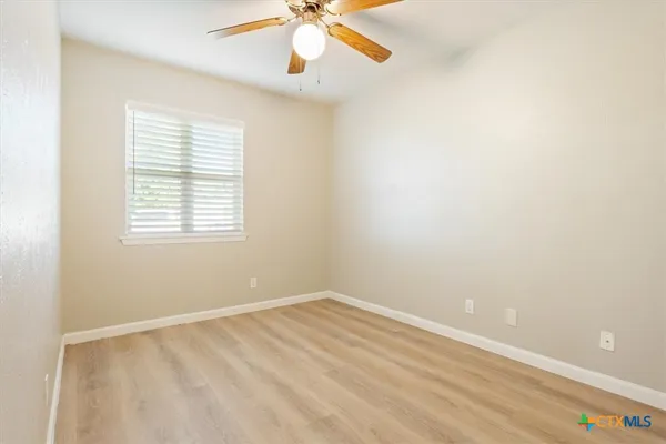 an empty room with a window and a ceiling fan