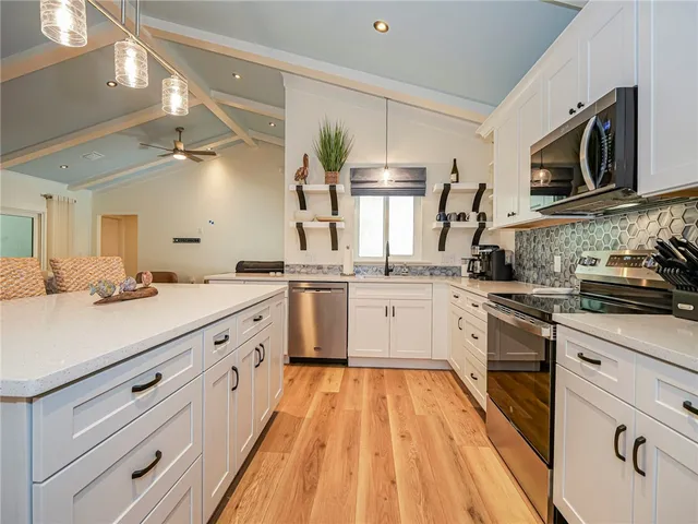 a kitchen with stainless steel appliances granite countertop a sink dishwasher a stove and a microwave oven with cabinets