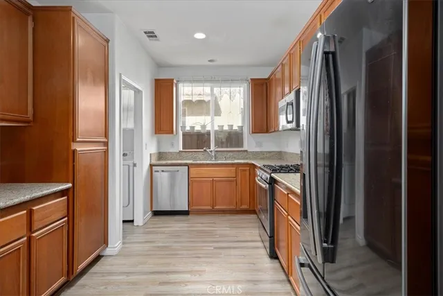 a kitchen with stainless steel appliances granite countertop a refrigerator and wooden cabinets