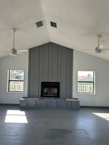 an empty room with windows fireplace and fans
