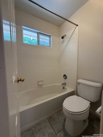 an empty room with a chandelier fan and windows