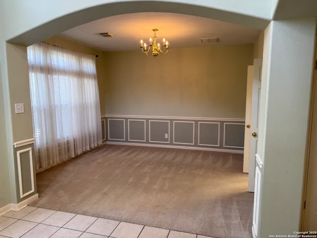 en empty room with windows and chandelier