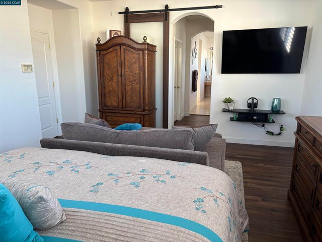 a bedroom with a bed a flat screen tv and dresser