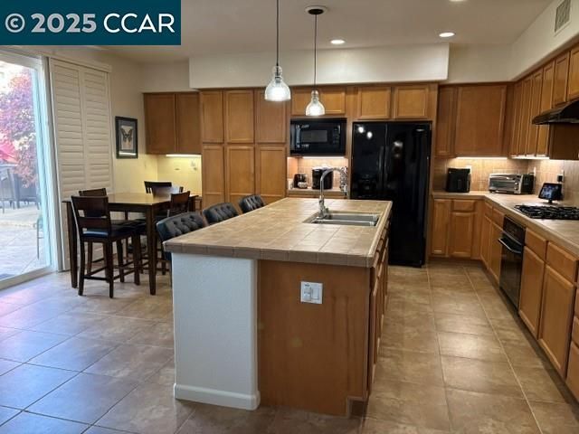 a kitchen with kitchen island granite countertop a sink a counter top space appliances and cabinets