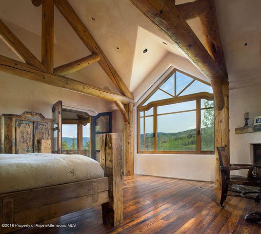 a bedroom with a bed a mirror on dresser and a large window