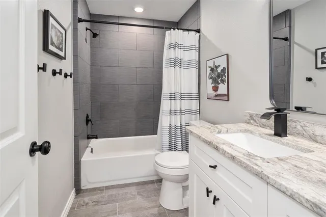 a bathroom with a bathtub shower sink vanity mirror and toilet