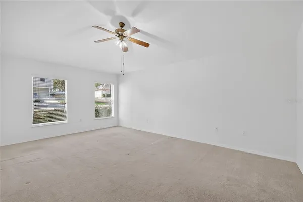 an empty room with windows and fan