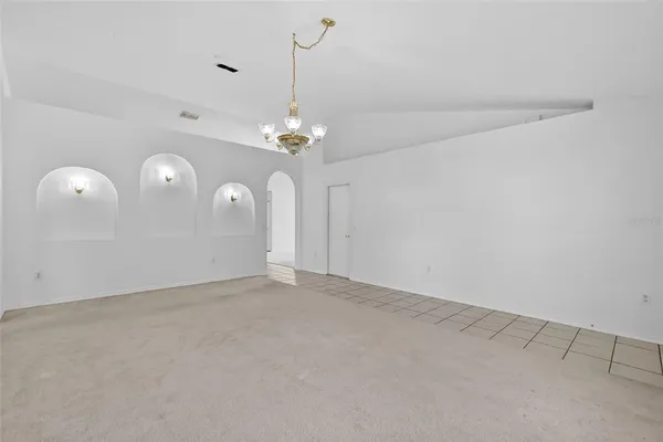 a view of an empty room with a chandelier fan