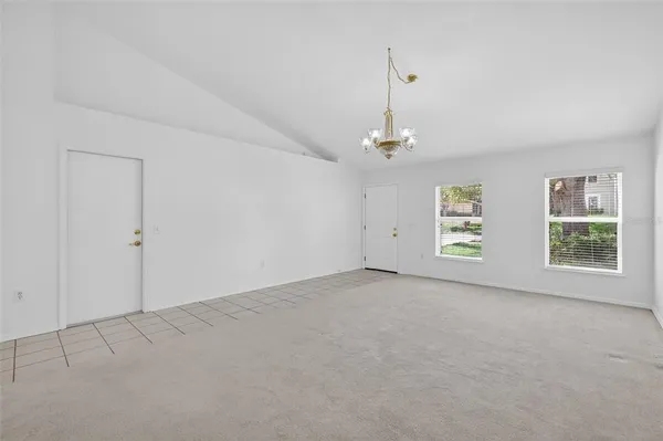 an empty room with windows and chandelier fan