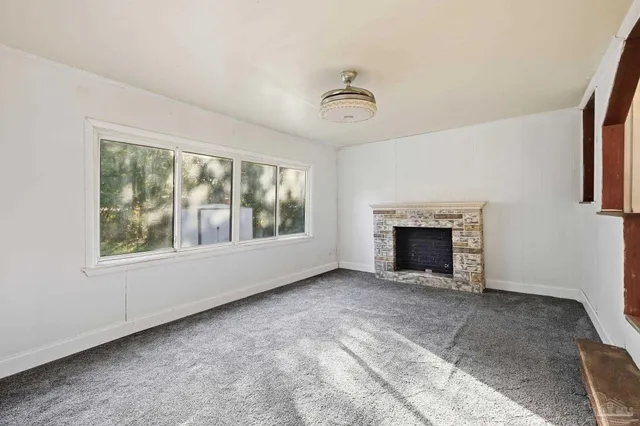 an empty room with windows and fireplace