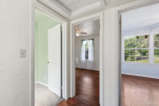 a view of a hallway with wooden floor and a room