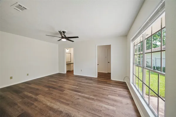 a view of empty room with wooden floor and fan