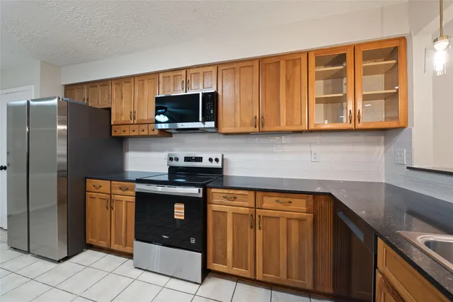 a kitchen with stainless steel appliances granite countertop a stove top oven a refrigerator and a sink