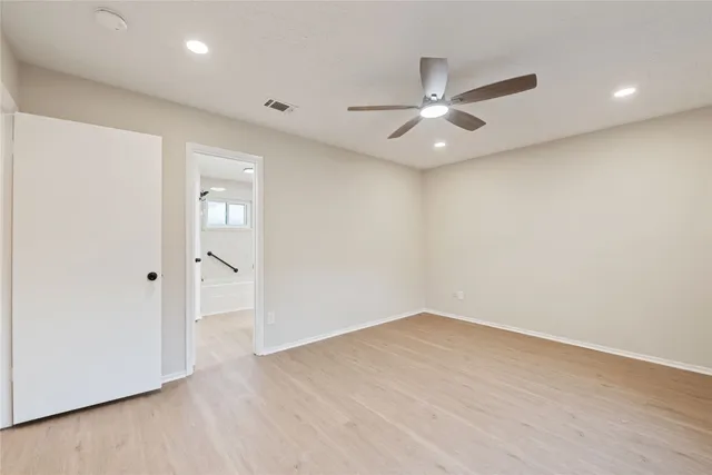 an empty room with wooden floor ceiling fan and windows