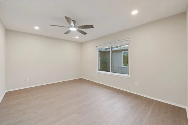 an empty room with a window and ceiling fan