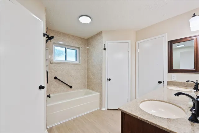a bathroom with a granite countertop tub sink and mirror