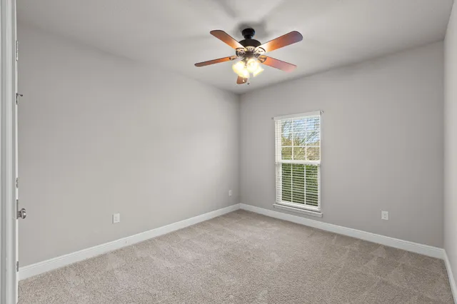 an empty room with window and chandelier fan