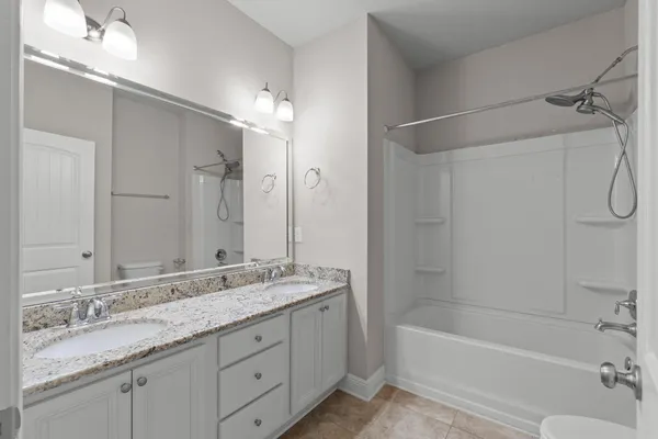 a bathroom with a granite countertop bathtub shower sink vanity and mirror